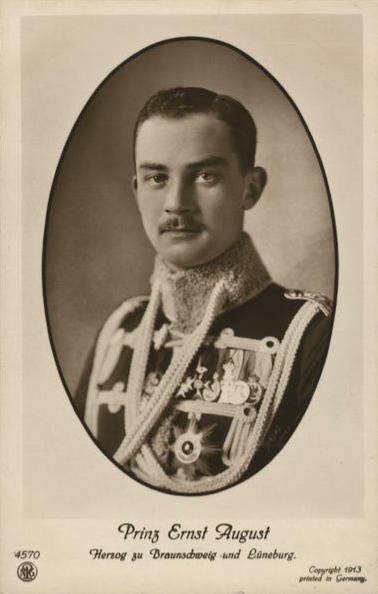 Black and white photo dated 1913 of Prince Ernst August dressed in a military tunic adorned with medals, orders and aiguillettes.