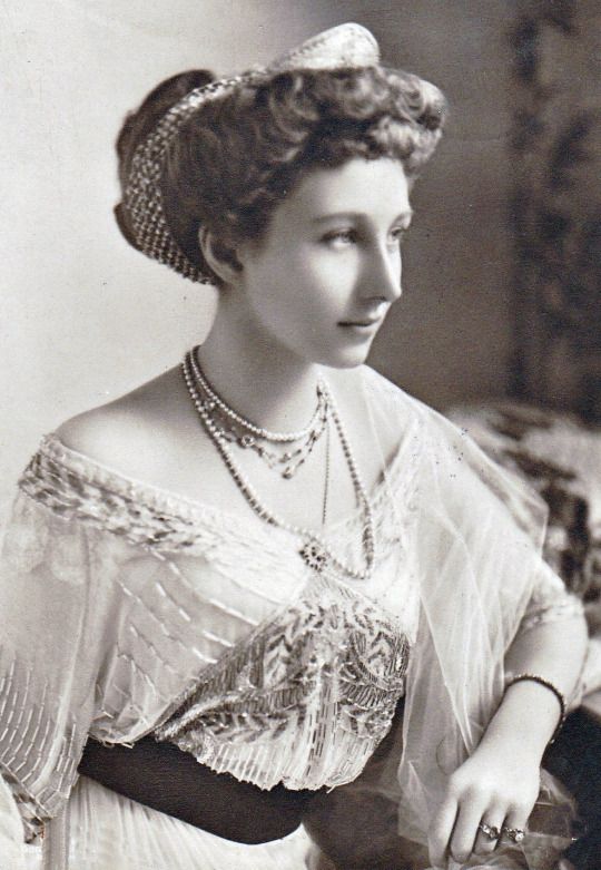 Black and white photo of Princess Viktoria wearing a beaded and embroidered gown, several necklaces and rings. 